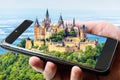 Hohenzollern Castle atop mount, Germany. Picture of famous fairytale Gothic castle on smartphone, amazing photograph of landscape