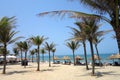 Hoi An, Da Nang, Vietnam - March 16, 2018: Tourists enjoying the sun on An Bang beach with lines of coconut trees, straw umbrellas