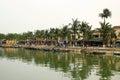 View on the Thu Bon River with traditional wooden boats and embankment with yellow buildings and palm trees Royalty Free Stock Photo