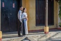 Happy Vietnamese couple of guy and girl near the old yellow wall in the city of Hoi An, Vietnam