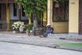 Old vietnamese woman in a straw hat sits on a street near home in the old city in Hoi An, Vietnam Royalty Free Stock Photo