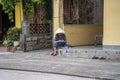 Old vietnamese woman in a straw hat sits on a street near home in the old city in Hoi An, Vietnam Royalty Free Stock Photo