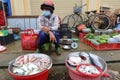 A man with a helmet and mask at a small stall in the Ba Le market in Hoi An