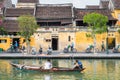 Hoi An, Vietnam: the old town riverside street with travelers in a boat and cycle rickshaws