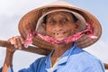 Hoi An, Vietnam: a smiling elderly Vietnamese lady, a street vendor, poses in a conical hat