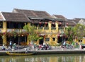 Local people, boats, yellow houses by the river, and tourists in Hoi An ancient town