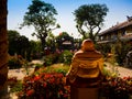 HOIAN, VIETNAM, SEPTEMBER, 04 2017: Back view of a budha in an ancient temple with a beautiful jarden with colorful