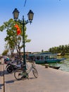 HOIAN, VIETNAM, SEPTEMBER, 04 2017: Bikes and motorcycles parked in a row, and some boats ofr tourist in the water in