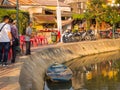 HOIAN, VIETNAM, SEPTEMBER, 04 2017: Unidentified man fishing in the border of the river whilse some people is walking