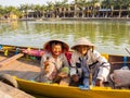 HOIAN, VIETNAM, SEPTEMBER, 04 2017: Unidentified old couple in the traditional boats in front of ancient architecture in