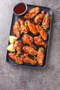 Hoisin chicken wings with sesame, green onion and lime served with sauce close-up in a plate. Vertical top view