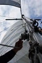 Hoisting tarpaulin at the mast on a sailboat. Active sport that moves on wind power by catching wind in the sails. Royalty Free Stock Photo