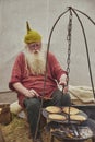 Hojbjerg, Denmark, August, 2022: Old man frying pancakes on a campfire