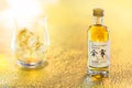 Small bottle miniature of single malt Yoichi from the Japanese maker Nikka Whisky on a golden surface.