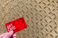 Hold a red gift card against golden plaid background.