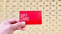 Holding a red gift card with golden plaid background.