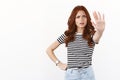 Hold it. Serious-looking bossy redhead caucasian girl in striped t-shirt pull hand in stop motion, forbid step further