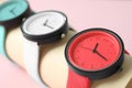 Holder with collection of stylish wrist watches on color background.