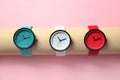 Holder with collection of stylish wrist watches on color background.