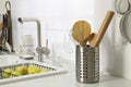 Holder with cooking utensils near sink on kitchen counter Royalty Free Stock Photo