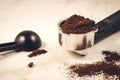 holder filled with ground coffee a black spoon/holder filled with ground coffee a black spoon on a marble background. Selective Royalty Free Stock Photo