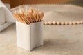 Holder with many toothpicks on beige table, closeup. Space for text