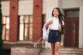 Holding an apple. School girl in uniform is outdoors near the building