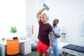 Sportsman holding barbells while visiting physical therapist