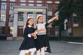Holding books. Two schoolgirls is outside together near school building Royalty Free Stock Photo