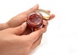 Holding a bottle of cosmetic on white background. The scrub is made out of strawberries.