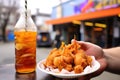 holding a bottled soda with fish and chips in the background