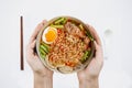 Holding bowl Hot and Spicy noodles and ingredients on isolated white background, Thai noodles with boil eggs in bowl with spoon an Royalty Free Stock Photo