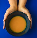 Holding a bowl of pumpkin soup