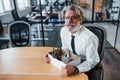 Holding box with tools. Mature businessman with grey hair and beard in formal clothes is in the office