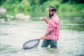 Holding brown trout. Man with fishing rods on river berth. Men fishing in river during summer day. Fly fisherman using Royalty Free Stock Photo