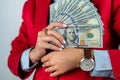 holding cash fans of dollars in hands in white shirt and red jacket  on solid color Royalty Free Stock Photo