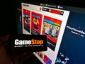 Holding cellphone with business logo of US retail company GameStop Corp. in front of website with online shop.