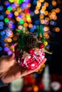Holding Christmas bauble decoration isolated on background with blurred lights. December season, Christmas composition Royalty Free Stock Photo