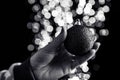 Holding Christmas bauble decoration isolated on background with blurred lights. December season, Christmas composition Royalty Free Stock Photo