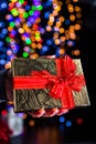 Holding Christmas gift isolated on background with blurred lights. December season, Christmas composition Royalty Free Stock Photo