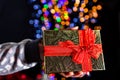 Holding Christmas gift isolated on background with blurred lights. December season, Christmas composition Royalty Free Stock Photo