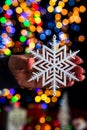 Holding Christmas snowflake decoration isolated on background with blurred lights. December season, Christmas composition Royalty Free Stock Photo