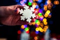 Holding Christmas snowflake decoration isolated on background with blurred lights. December season, Christmas composition Royalty Free Stock Photo