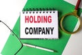 HOLDING COMPANY text on notebook on green paper