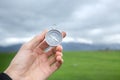 Holding a compass against the background of a green field during the day Royalty Free Stock Photo