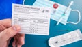 Holding a Covid-10 vaccination record card with vaccine vial, syringe and facial mask and faqs