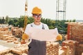 Holding document. Young construction worker in uniform is busy at the unfinished building Royalty Free Stock Photo