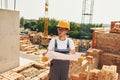 Holding document. Young construction worker in uniform is busy at the unfinished building Royalty Free Stock Photo