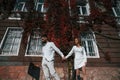 Holding each other by hands. Beautiful young couple is together on the street against old building Royalty Free Stock Photo