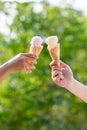 Holding and eating ice cream in the park. Hands holding melting ice cream waffle cone in hand on summer nature light background . Royalty Free Stock Photo